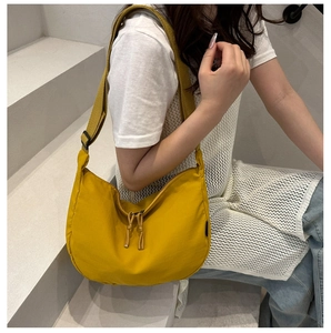 Detail of ginger yellow dumpling crossbody bag with adjustable strap worn by model