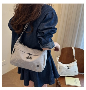 Dettaglio borsa a tracolla in nylon grigio chiaro con tasche a zip e trama increspata