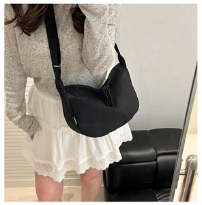 Detail view of black crescent canvas crossbody bag with drawstring design and logo tag
