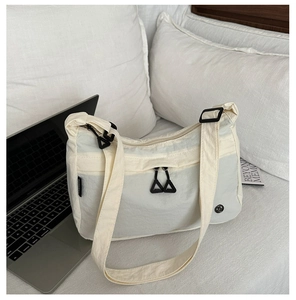 Dettaglio della borsa a tracolla in nylon bianco panna con tasca a zip e etichetta del marchio