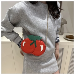 Detailed view of mini cherry shaped crossbody bag with gold chain strap on model
