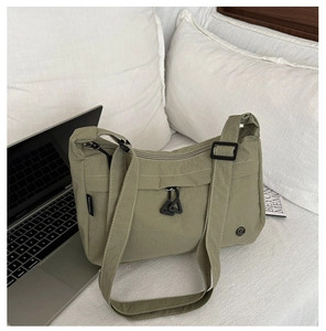 Dettaglio borsa a tracolla in nylon verde matcha con tracolla regolabile su sfondo laptop