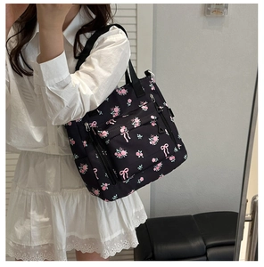 Detailed view of large black nylon tote bag with pink rose prints on a female model