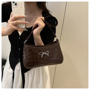 Détail du sac à bandoulière marron foncé à motif croco avec pendentif noeud argenté