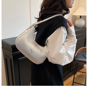 Zilveren metallic hobo tas met strikgesp getoond in een stijlvolle binnenomgeving