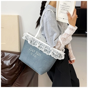 Close-up of light blue denim tote bag featuring white lace trim and embroidery detail
