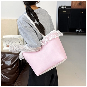 Gros plan d'un sac cabas en toile rose avec dentelle blanche et détails de lettres gaufrées