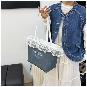 Gros plan sur un sac cabas en denim gris avec bordure en dentelle blanche et broderie