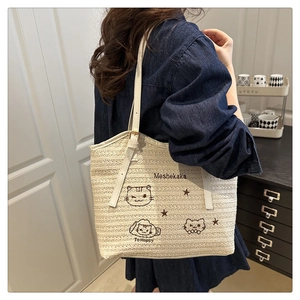 Detailed embroidery of a cartoon cat on a beige woven tote bag with star patterns