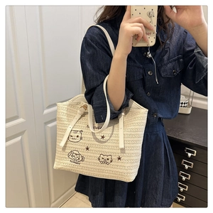 Détail du sac fourre-tout tissé avec broderie chat et bandoulière en cuir synthétique blanc