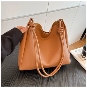 Détail d'un grand sac cabas en simili cuir caramel avec bandoulière nouée élégante