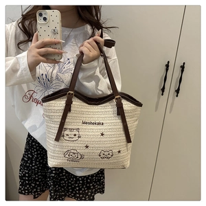 Detail of woven tote bag featuring cute cat embroidery and premium brown leather handles