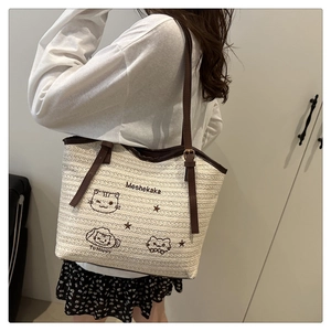 Détail d'un cabas tissé avec broderie chat et bandoulière en cuir réglable