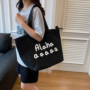 Minimalist large black canvas tote bag with white lettering shown on a female model