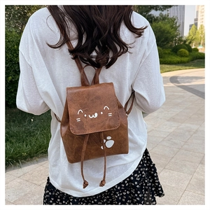 Close-up of brown mini backpack featuring cute white kitten prints and retro PU texture
