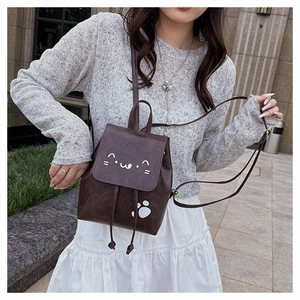 Détail du sac à dos en similicuir marron avec broderie chat et empreintes de pattes