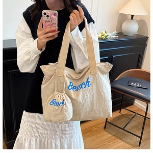 Details der beigen Kordelzug-Tasche mit Beach-Schriftzug und passender kleiner Geldbörse