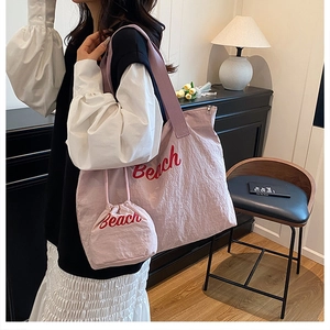 Borsa tote in tela rosa con scritta Beach rossa indossata da una modella in interno
