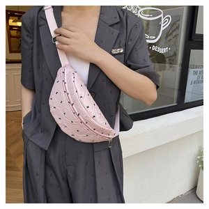 Detail of pink half-moon crossbody bag with black bow print and adjustable strap