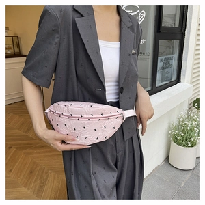 Detail of pink pleated waist bag with rabbit pattern on female model in street setting
