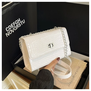 Detail of white crocodile embossed handbag with silver chain strap and metal swivel lock