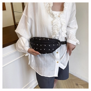 Detail of black crossbody chest bag with white cartoon bear print and silver metal zipper