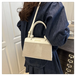 Detail showing the mixed material texture of linen and PU leather on the beige shell bag