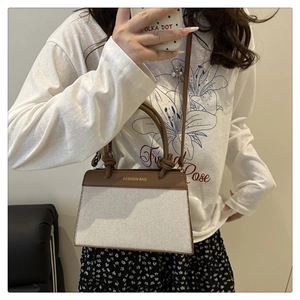 Detail of canvas and brown leather tote featuring knotted handle and gold lettering