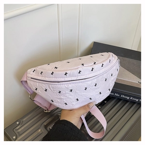 Close-up of pink quilted waist bag with black letter embroidery and adjustable strap