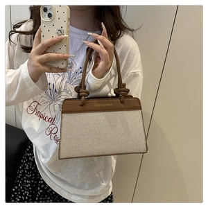 Detail of high-density canvas handbag with brown leather trim and fashion logo