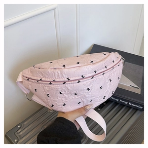 Detailed view of pink crossbody bag featuring embossed K pattern on a travel suitcase