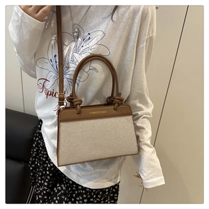 Detail view of contrast linen shell bag showing leather handles and fashion bag stamp