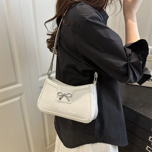 Sac sous le bras blanc à motif crocodile avec nœud argenté porté par le mannequin