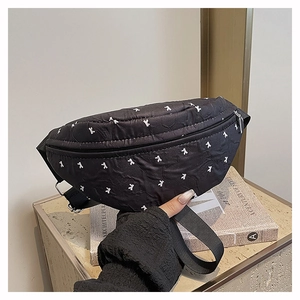 Detail of black quilted crossbody bag with white K pattern and silver buckle
