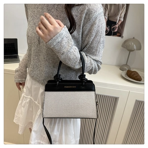 Detail of trendy bicolor canvas and leather shoulder bag with gold 'FASHION BAG' text