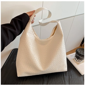 Detail of cream woven leather tote bag showing texture and wide shoulder strap