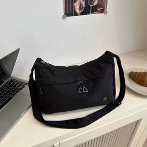 Detail of minimalist black nylon tote bag with functional zippers and water-resistant texture