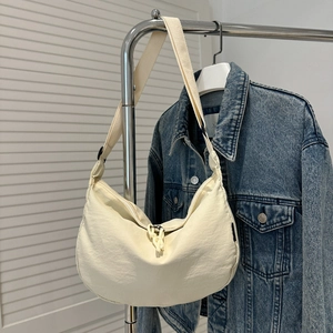Detail van crème halvemaanvormige crossbodytas met verstelbare riem en ritsdecoratie