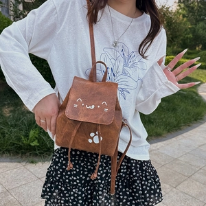 Petit sac à dos marron avec motifs de chat mignons dans un jardin naturel extérieur