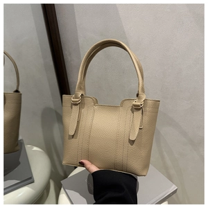 Detailed macro view of beige lychee grain leather texture and gold-tone metal buckles