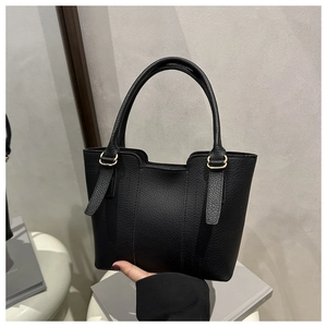 Detail of black lychee grain leather tote bag featuring gold hardware and elegant stitching