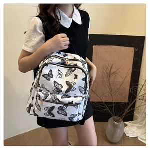 White backpack with black butterfly print featuring large capacity and gold zippers