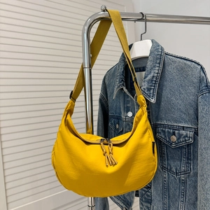 Detail van een felgele nylon tas in halvemaanvorm met dubbele rits en brede riem