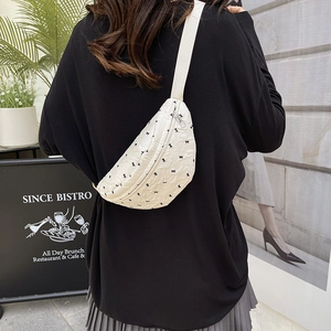 White quilted crescent bag with black bow print and adjustable crossbody strap