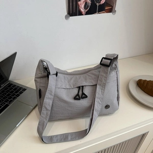 Macro shot of gray nylon tote bag showing water-resistant texture and metal zipper detail