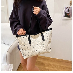 Detail of white tote bag with black bow pattern and premium leather trim straps