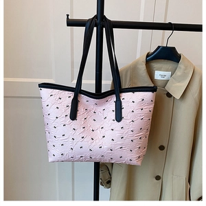 Detail of pink pleated tote bag with black bow patterns and leather shoulder straps