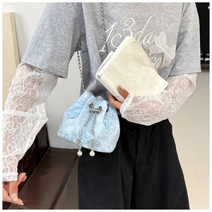 Detail of light blue embroidered bucket bag with pearl chain and 3D butterfly design