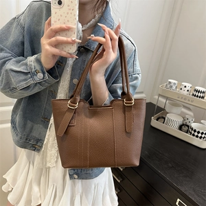 Minimalist brown pebbled leather bucket bag with top handle and gold metal hardware