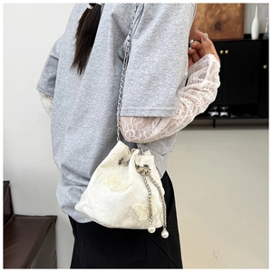 Detail of white butterfly embroidery and pearl charms on drawstring bucket bag